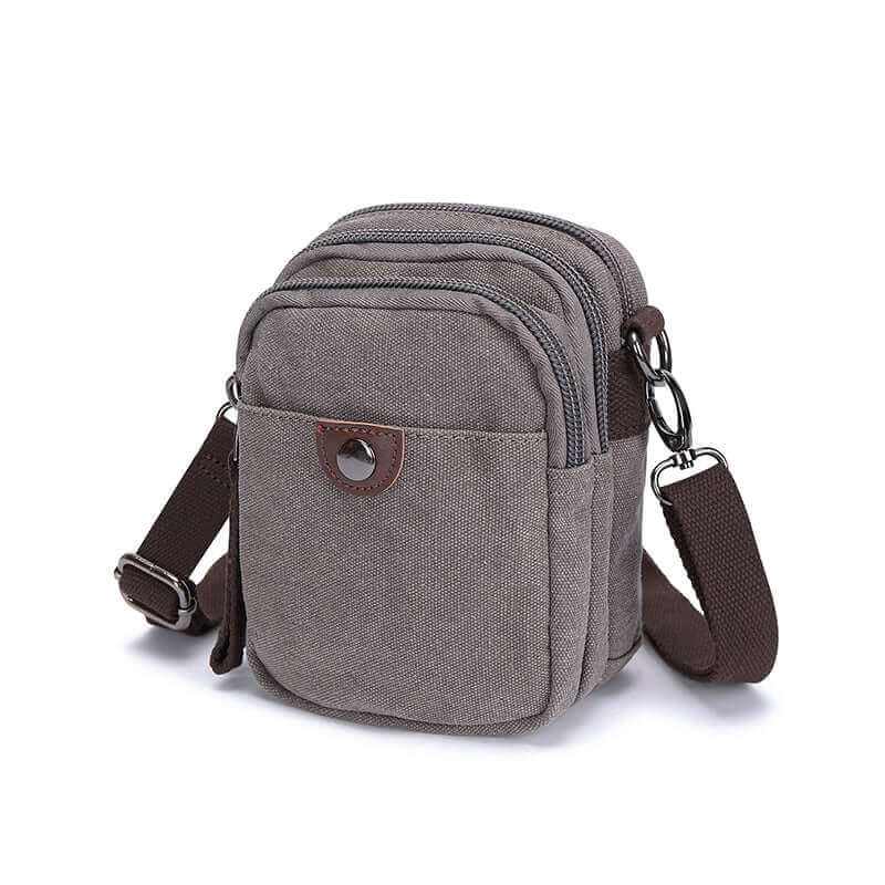 Grey canvas small crossbody bag with brown strap.