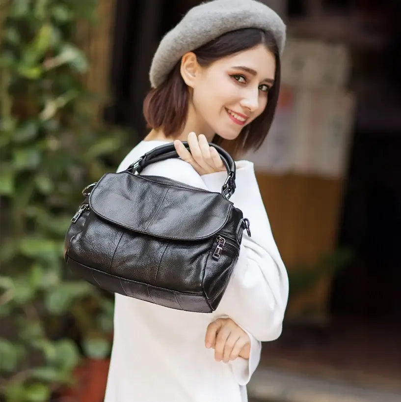 Model holding black leather bag in hand with minimalist outfit.