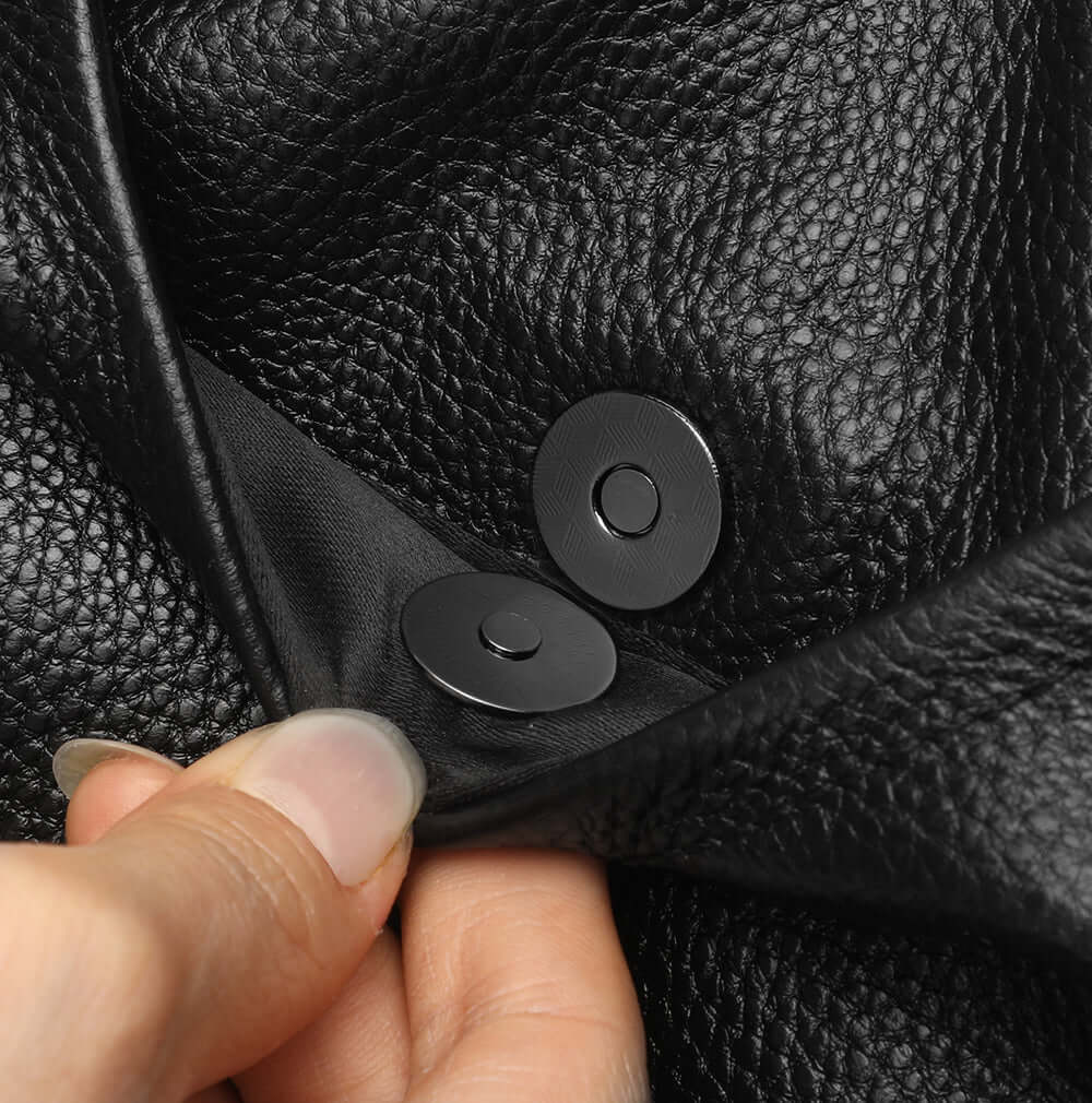 Close-up of a hand adjusting a button on a black leather backpack.