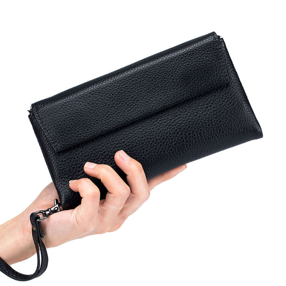 Black leather envelope long wallet being held in hand, showing its compact size.