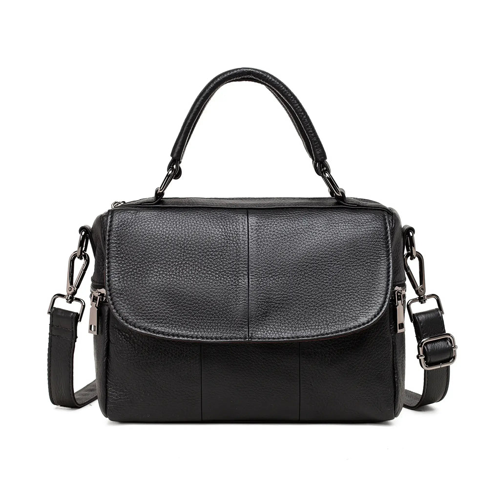 Black leather handbag shown with top handle and removable long strap.