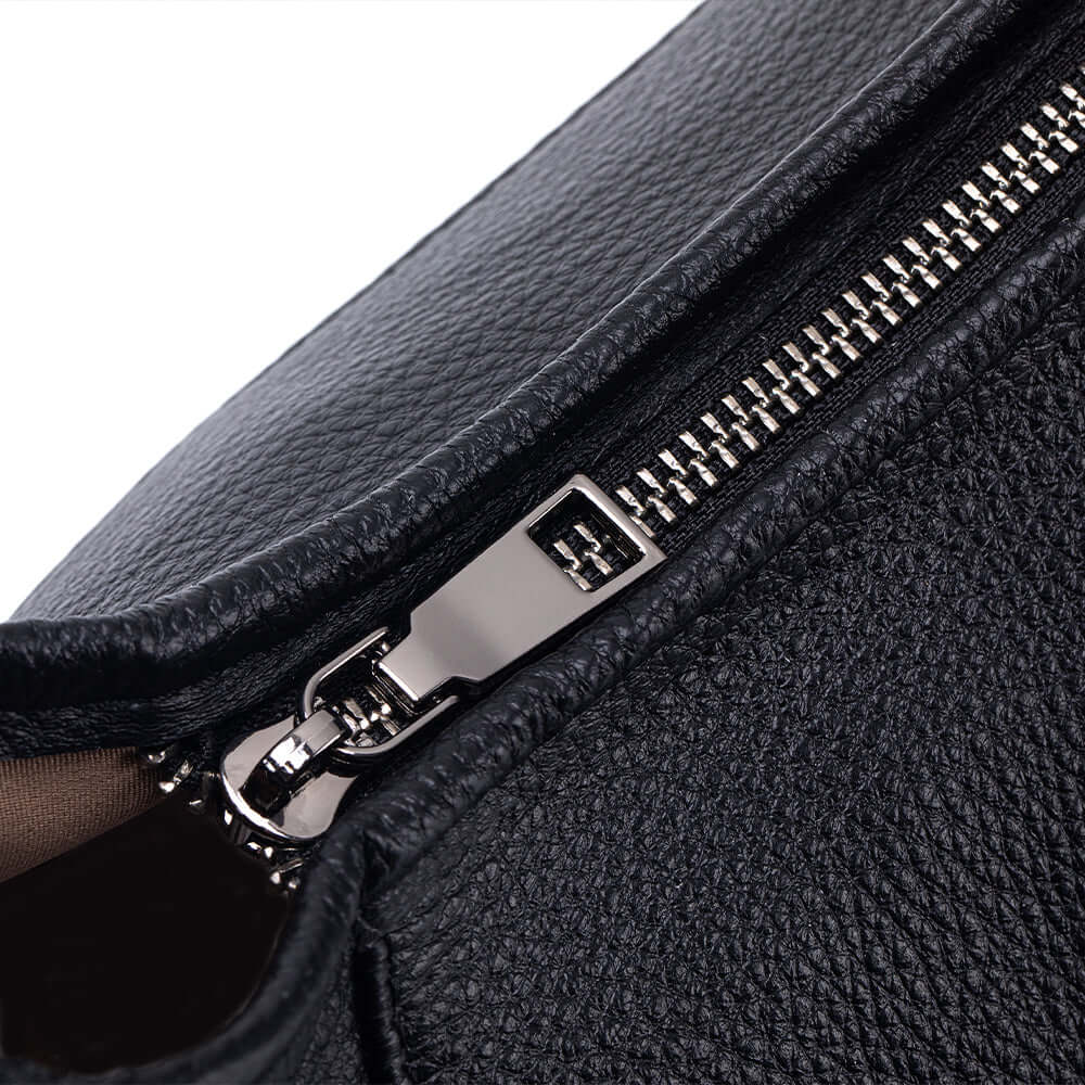Close-up of a black leather bag with a silver zipper.