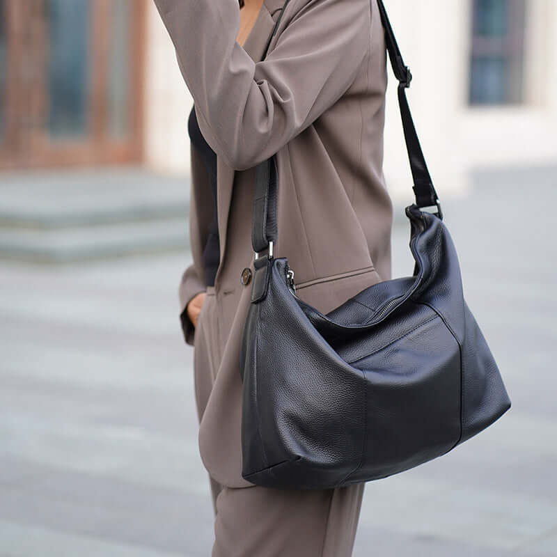 Black leather shoulder bag worn over the shoulder by a model.