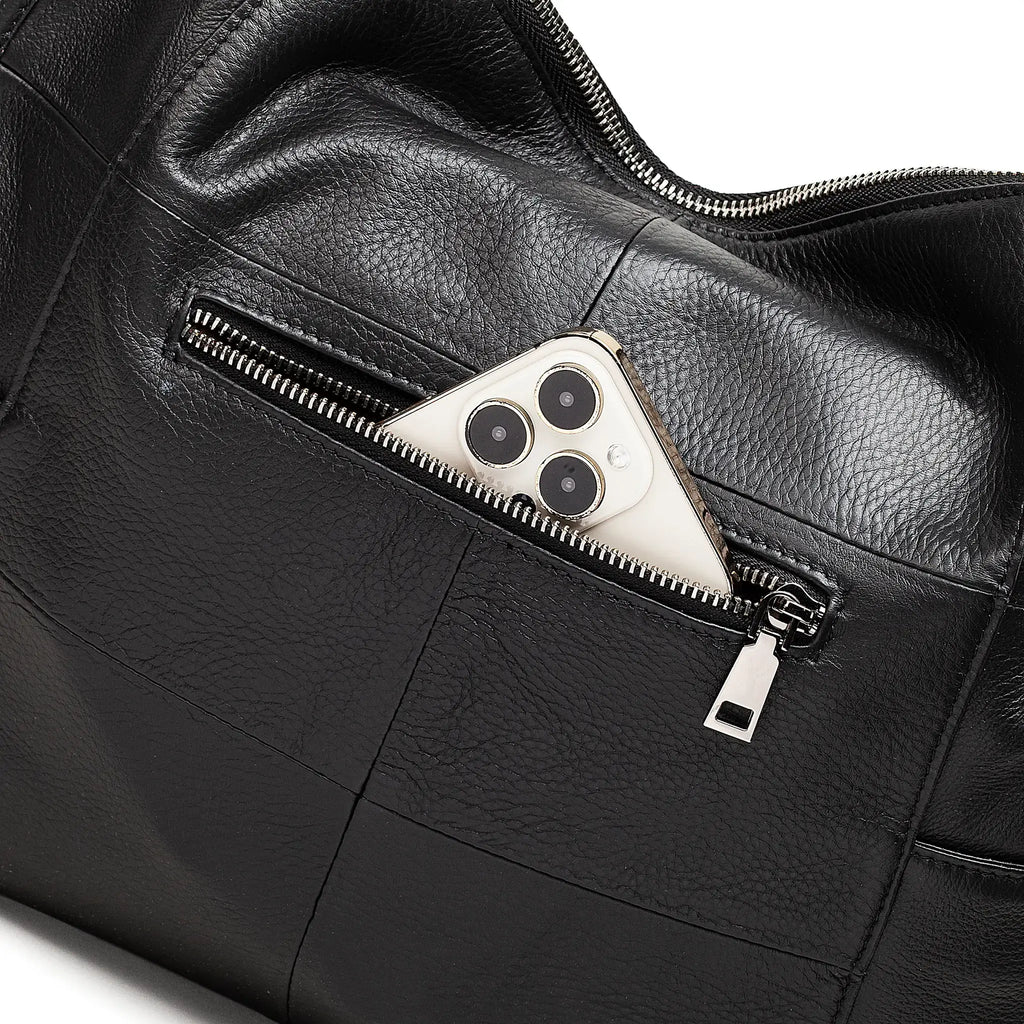 Black leather bag with a zipper pocket containing a smartphone.
