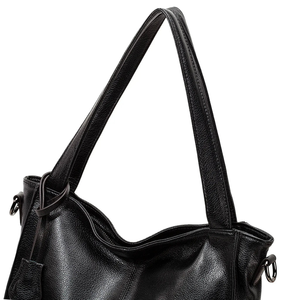 Black leather tote bag held by hand in elegant pose