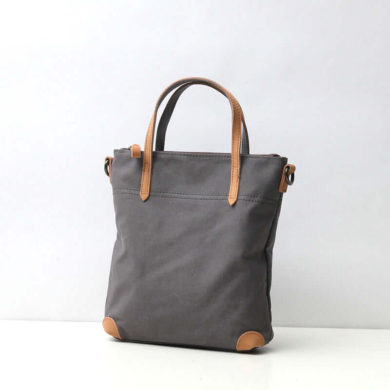 Grey canvas handbag with tan leather trim.