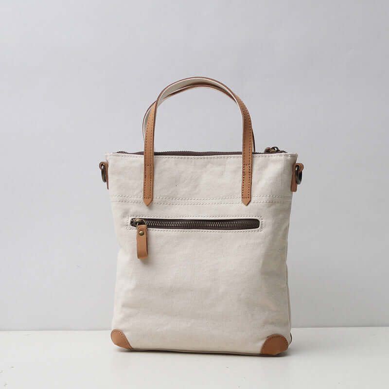 Back zipper pocket of white canvas handbag.