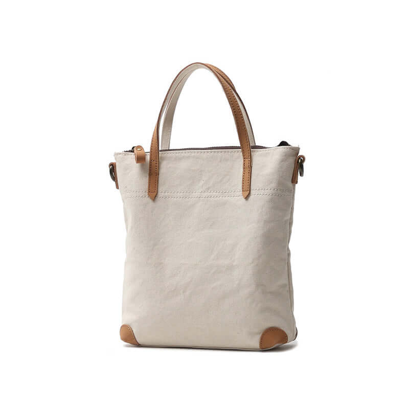 White canvas handbag with leather straps and base corners.