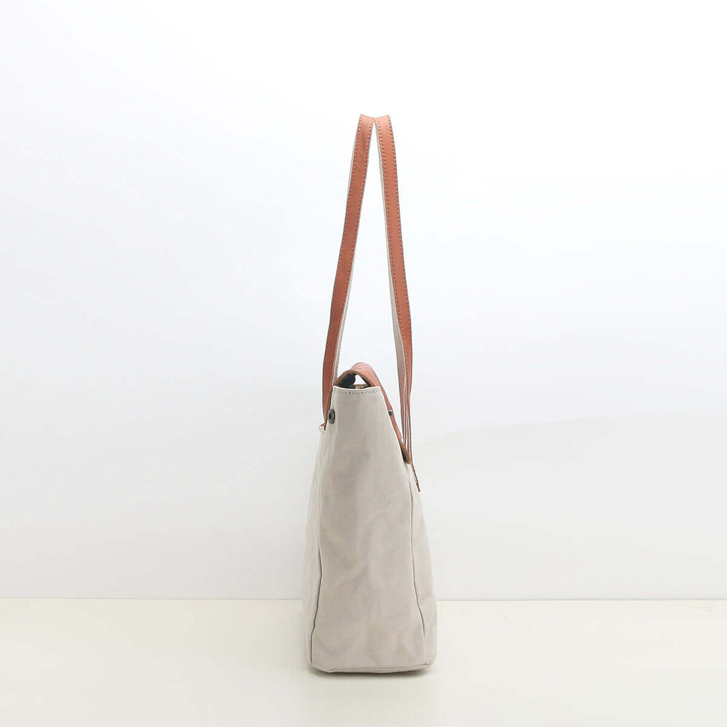Slim side profile of white canvas shoulder tote bag.