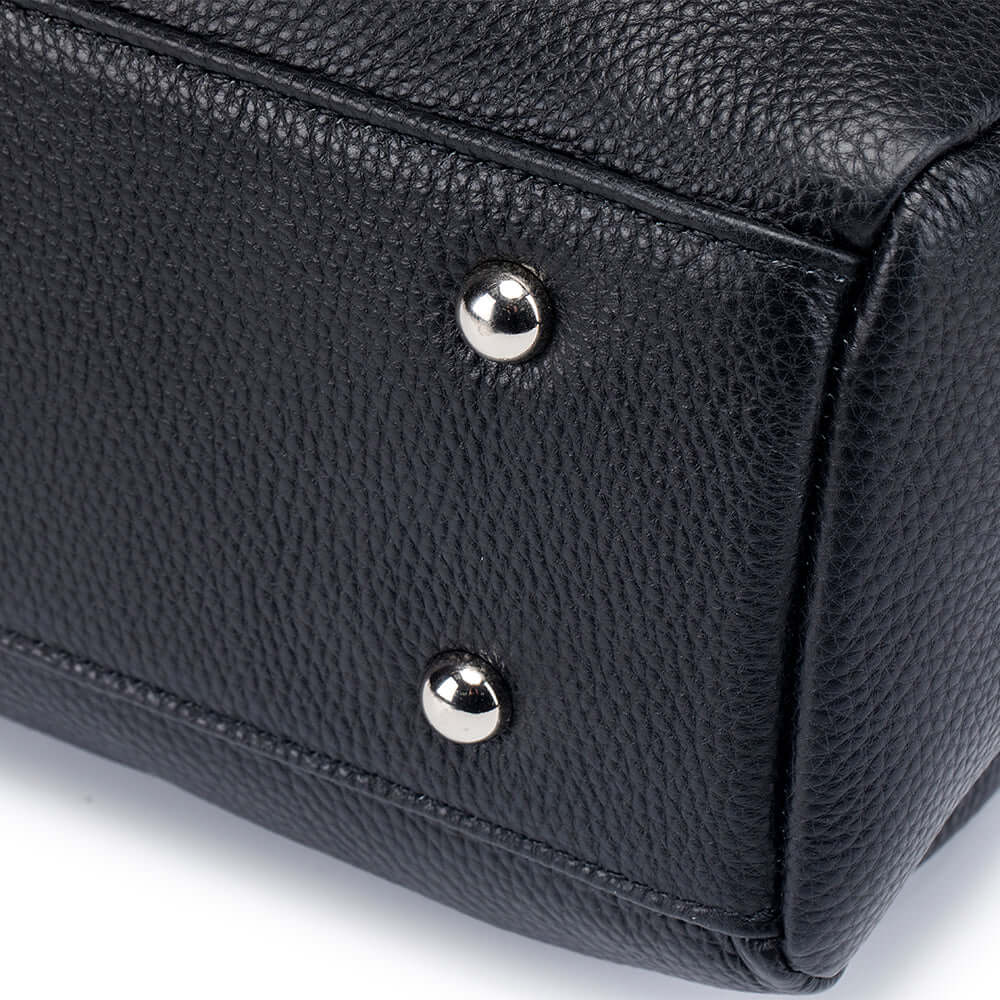 Close-up of a black leather handbag with silver buttons