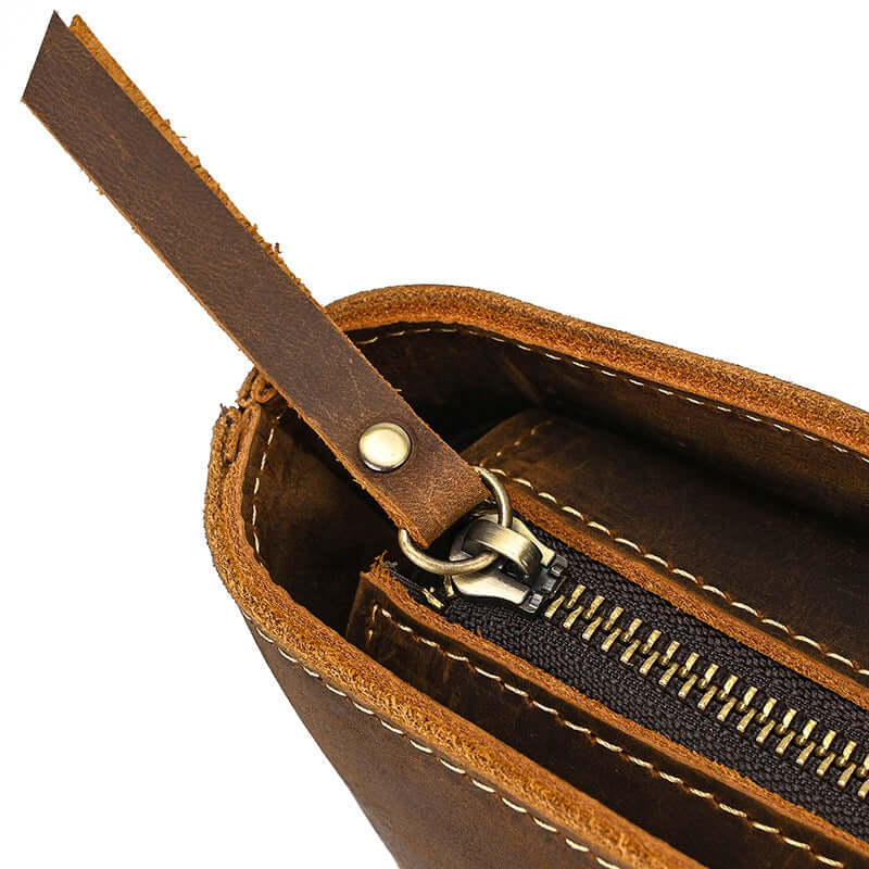 Close-up of a brown leather bag with a zipper and strap