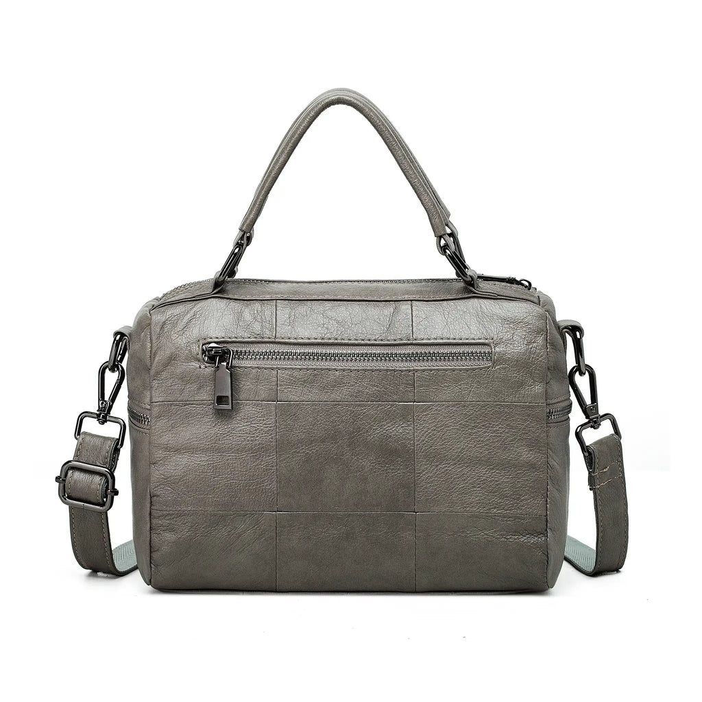 Grey leather bag with adjustable long strap for crossbody carry.