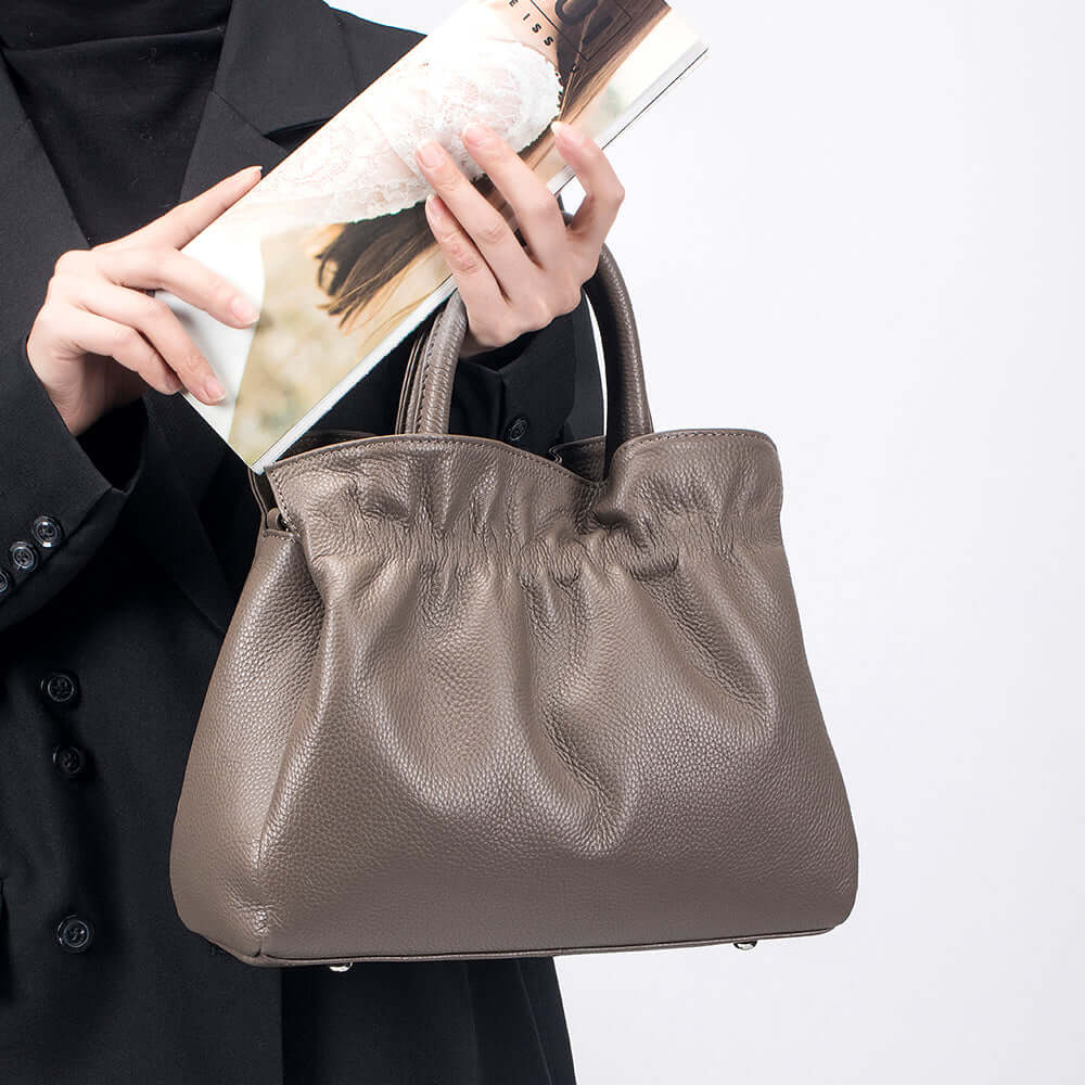 Person holding a grey leather handbag