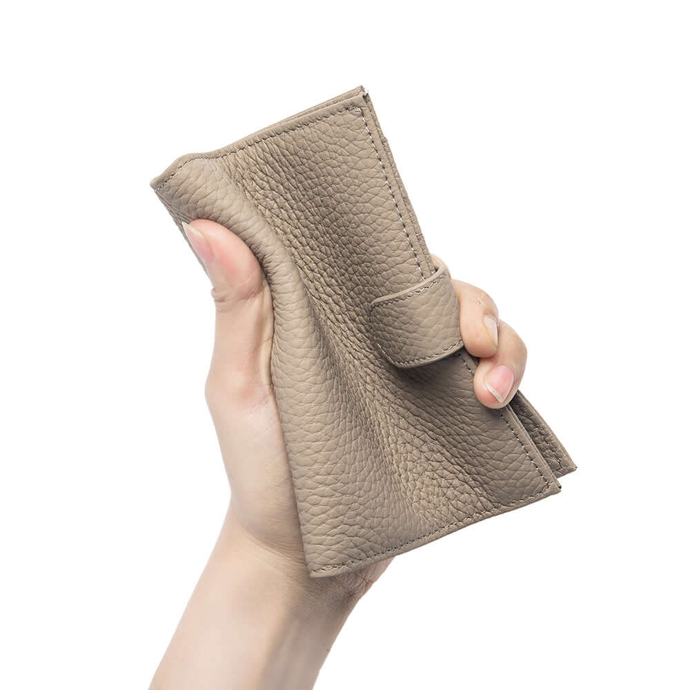 Hand holding a grey leather passport wallet.