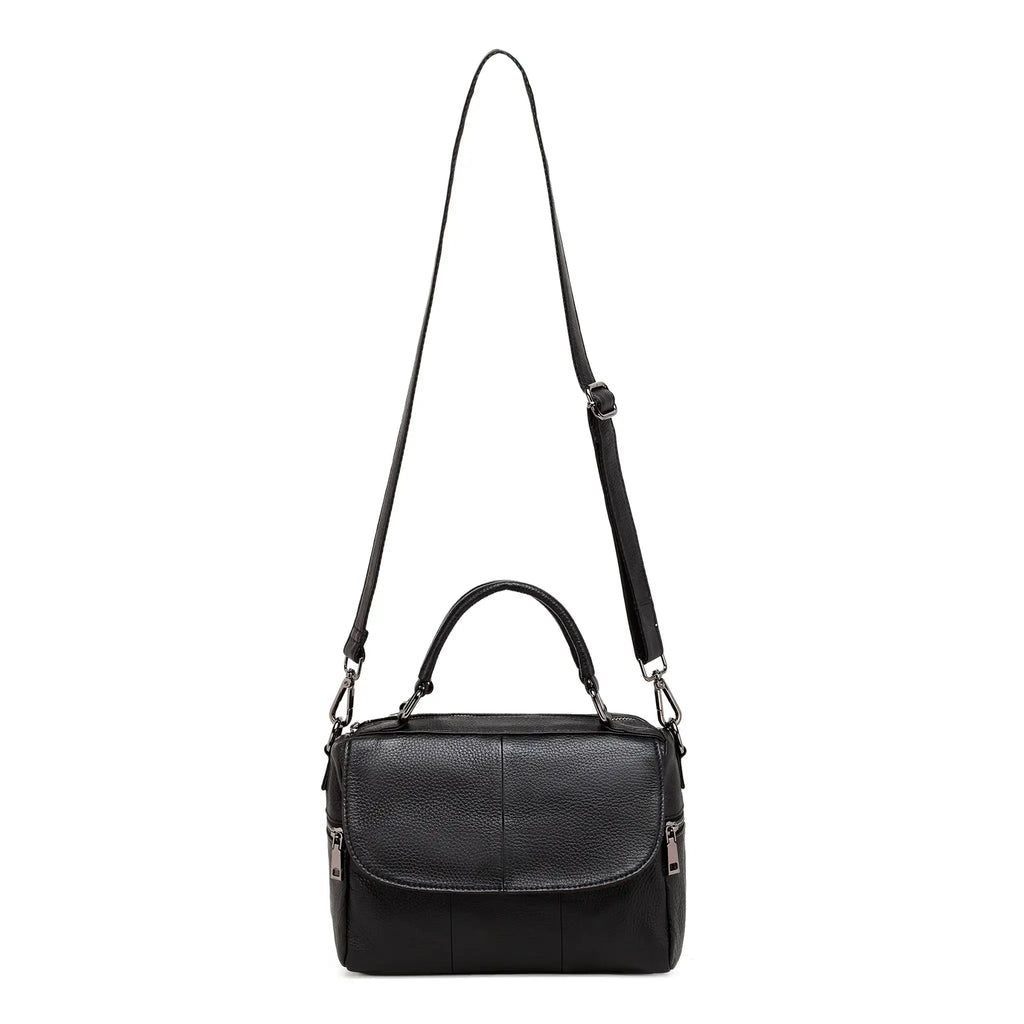 Black leather handbag with adjustable long crossbody strap displayed upright.