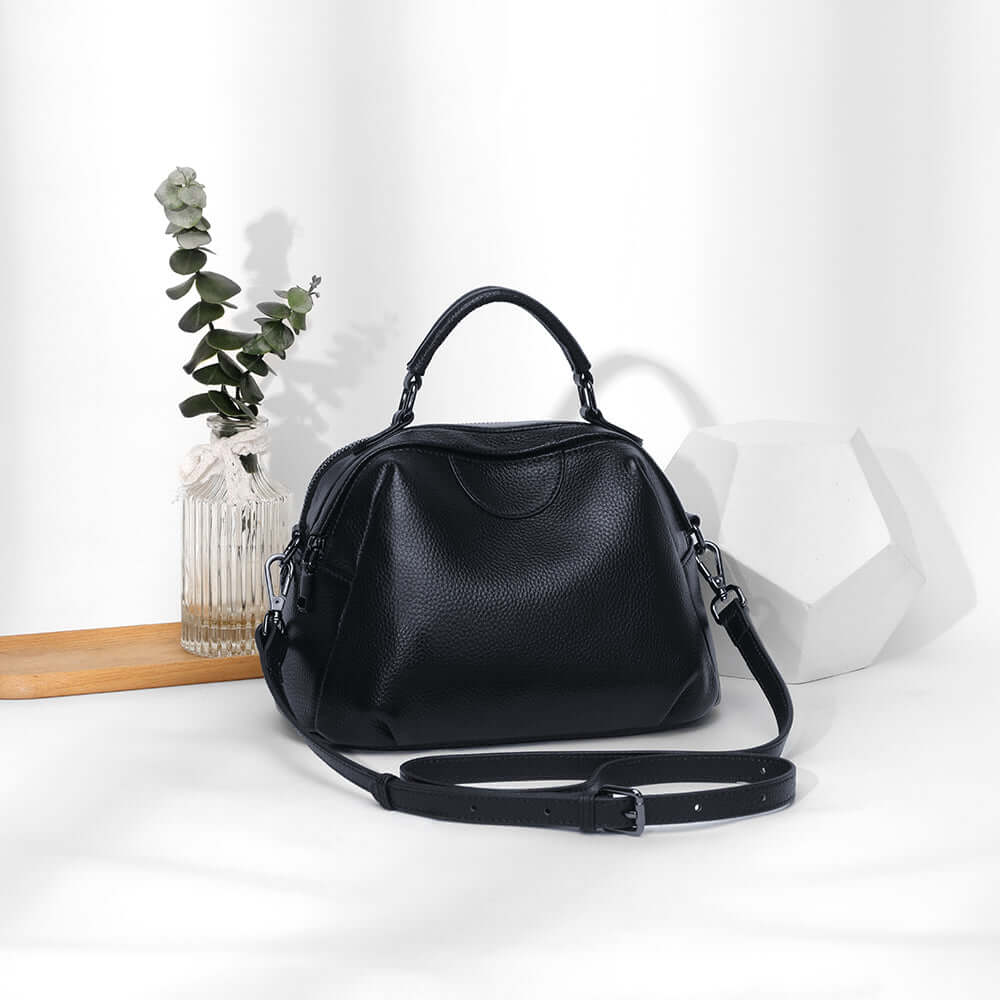 Black leather handbag displayed on table