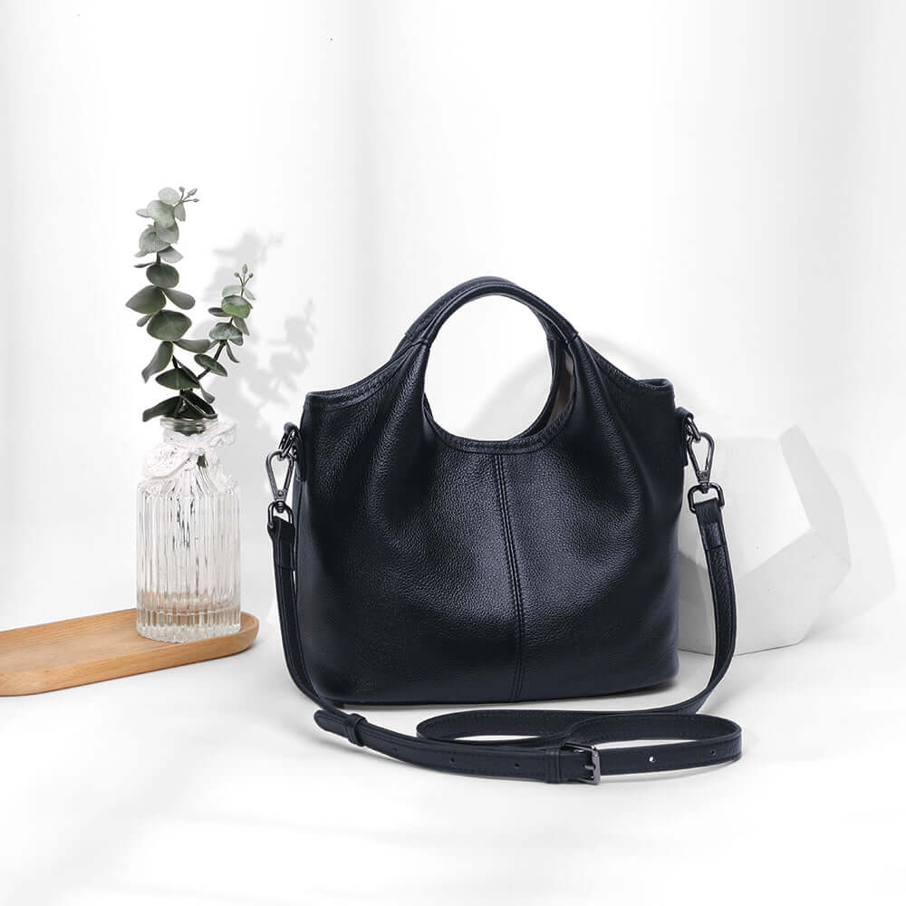 Black leather shoulder bag styled in studio scene