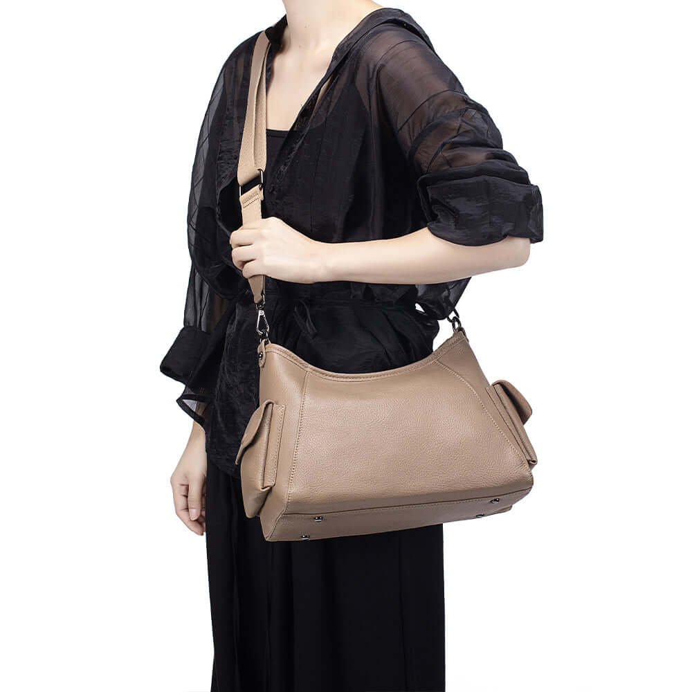 Woman carrying khaki leather shoulder bag on shoulder.