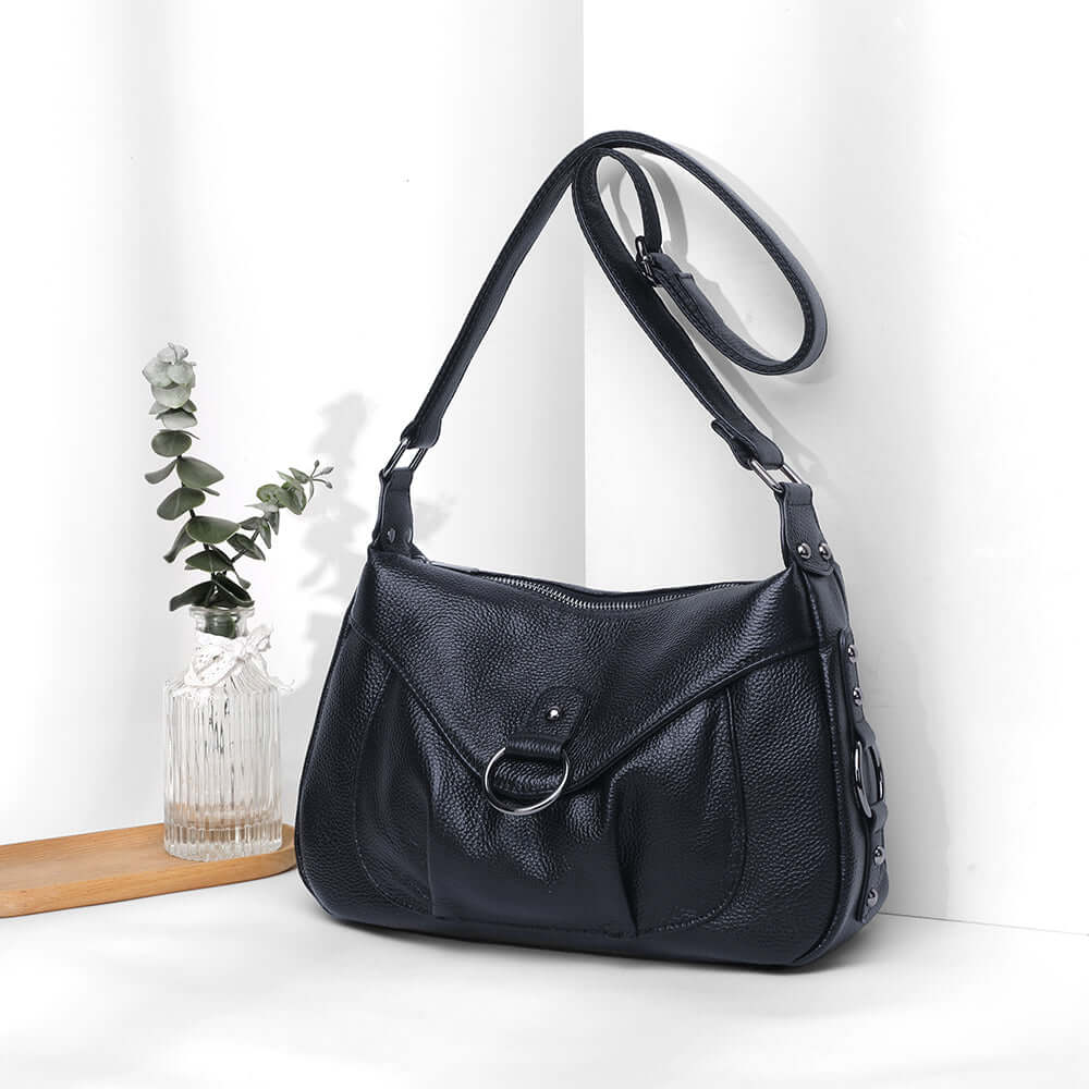 Black leather shoulder bag displayed in a lifestyle setting