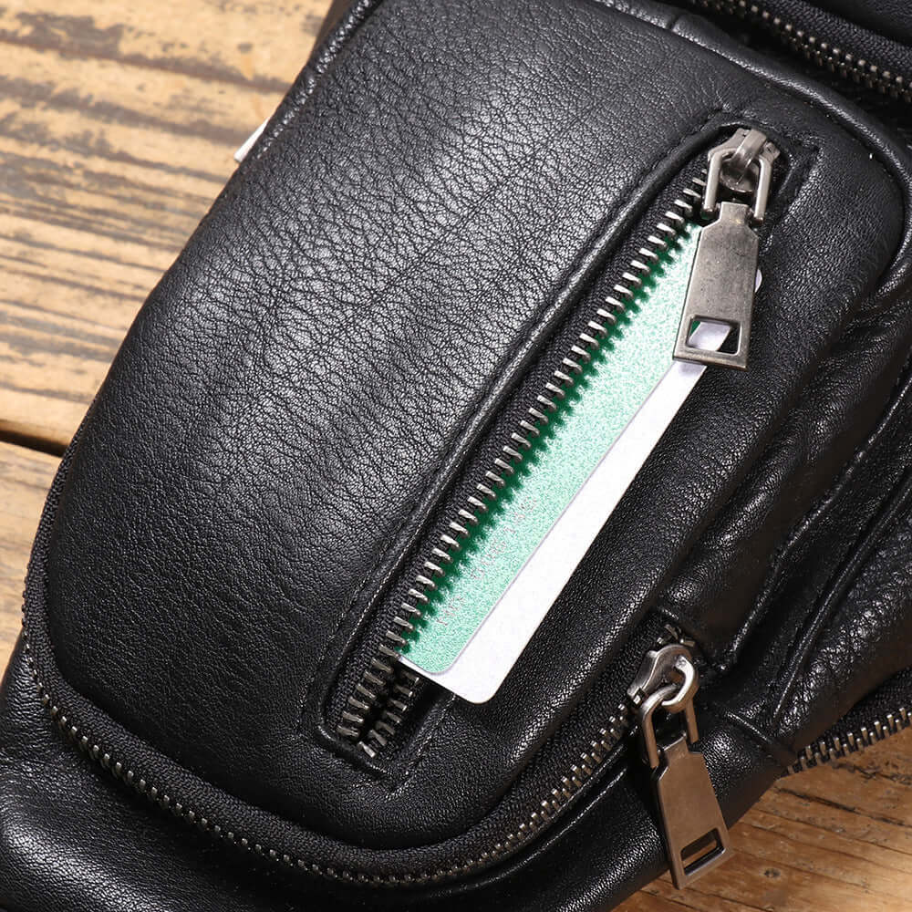 close-up of zipper pocket on black leather sling bag