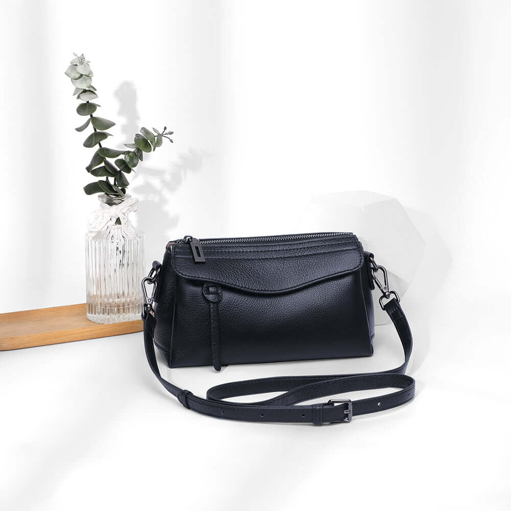 Women holding a black small leather shoulder bag in hand strap mode