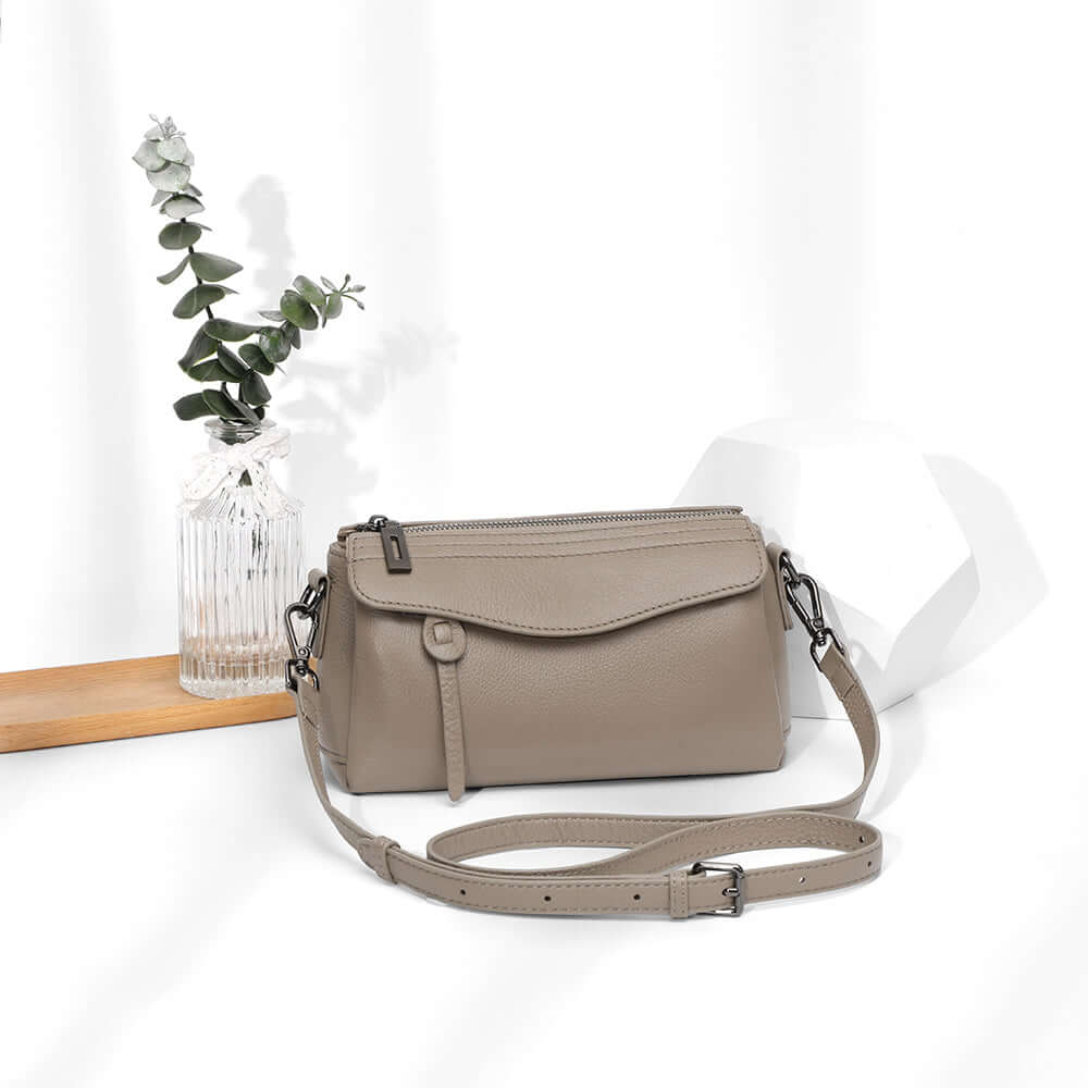 Women’s taupe leather mini bag worn on shoulder with long strap