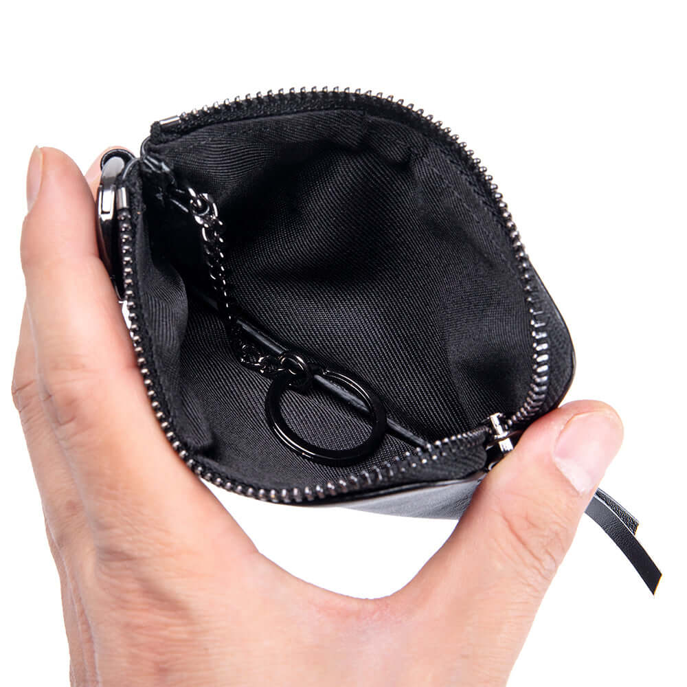 Hand holding a black zippered pouch wallet with a key inside.