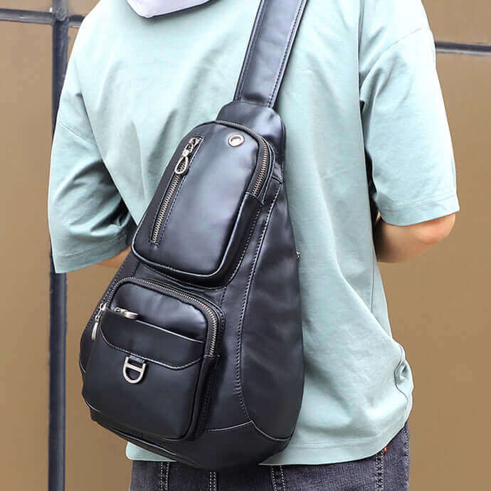 Men's leather sling bag displayed with essentials, demonstrating its large storage capacity.