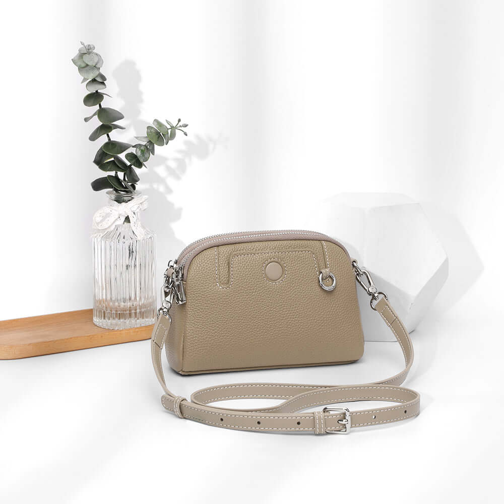 Angled front view of mini leather crossbody bag highlighting curved top.