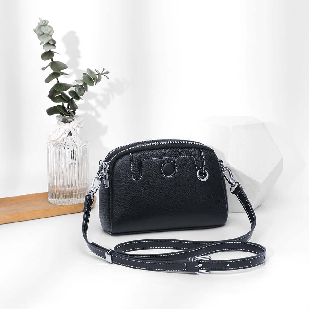 Mini leather crossbody bag styled in a minimal setup with decorative props