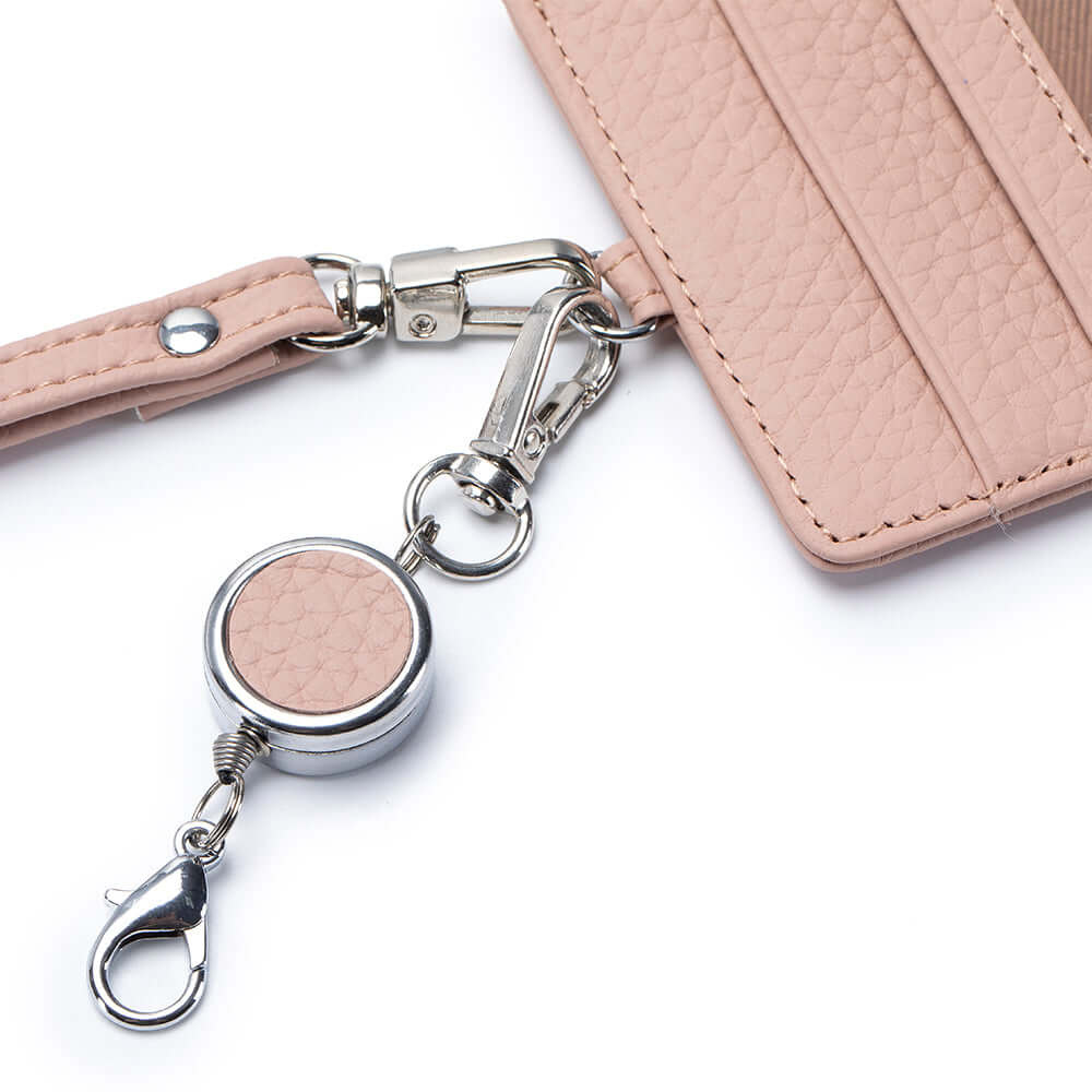 Pink keychain with metallic clasp attached to a pink wallet on a white background