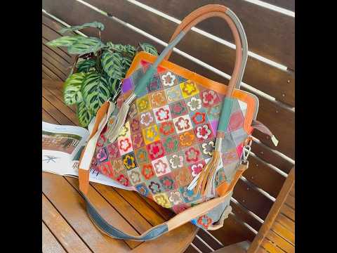 Woman wearing leather tote bag as crossbody with floral design.