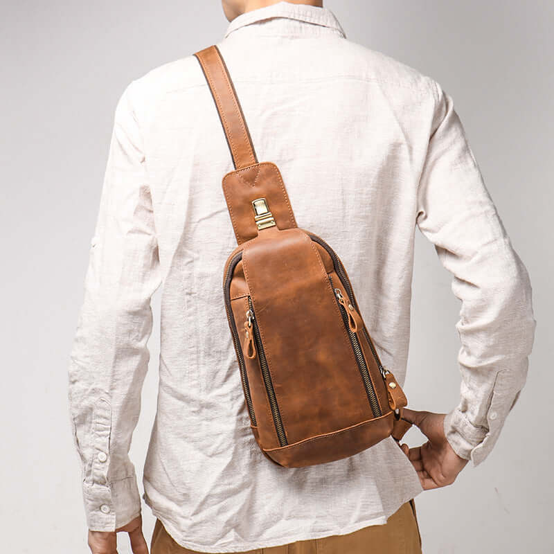 side view of model carrying men’s leather sling bag