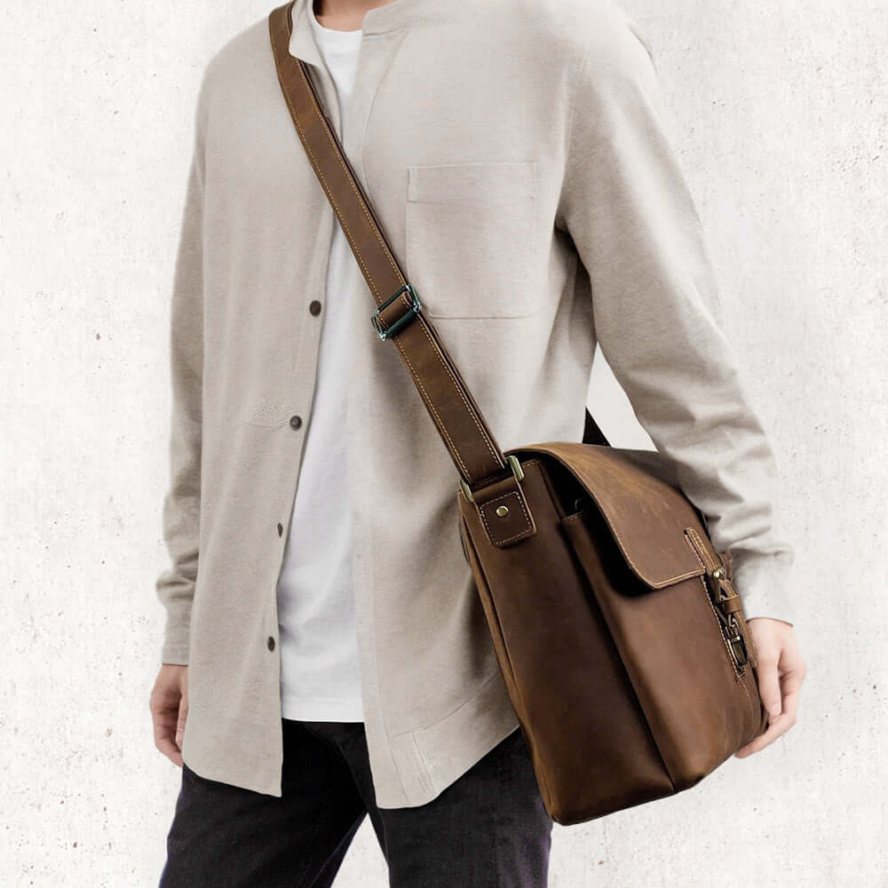 Man traveling with a leather messenger bag on his shoulder.