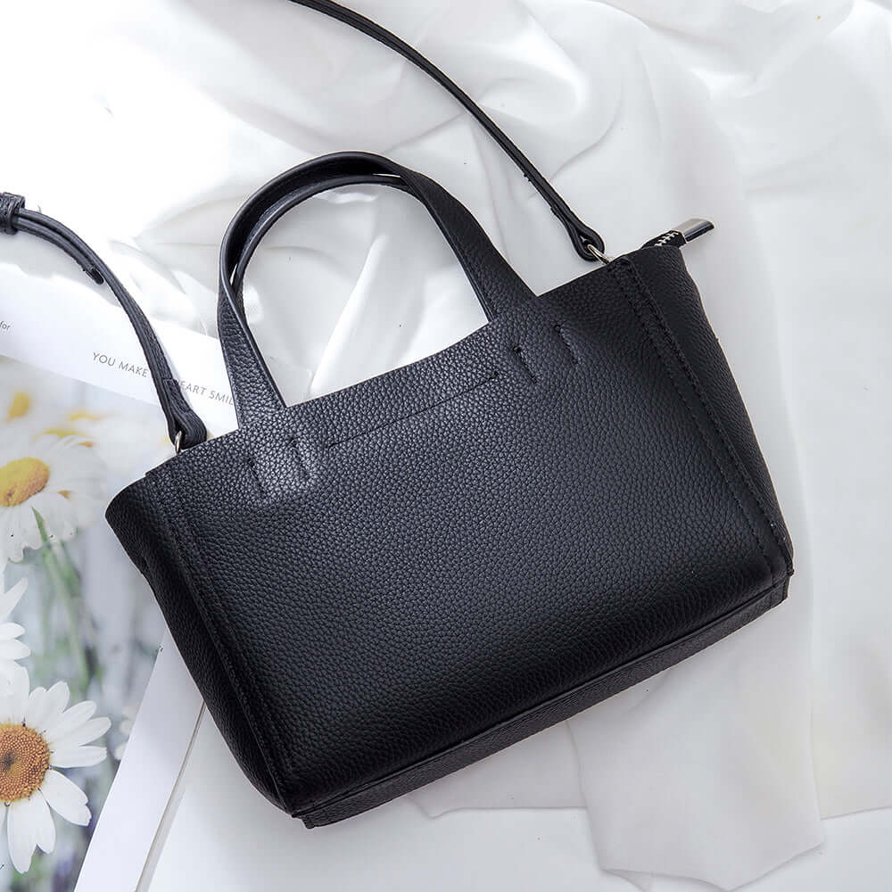 Woman carrying versatile black leather handbag crossbody style – chic and minimal.