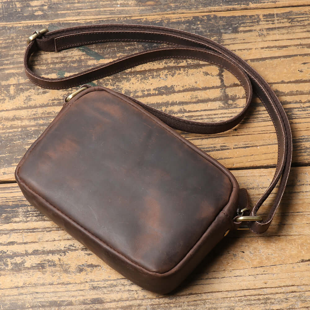 small vintage leather bag laying flat with strap