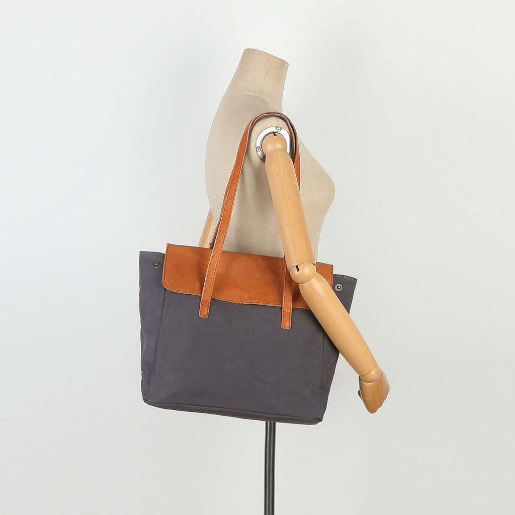 Grey canvas tote bag worn on shoulder by mannequin.
