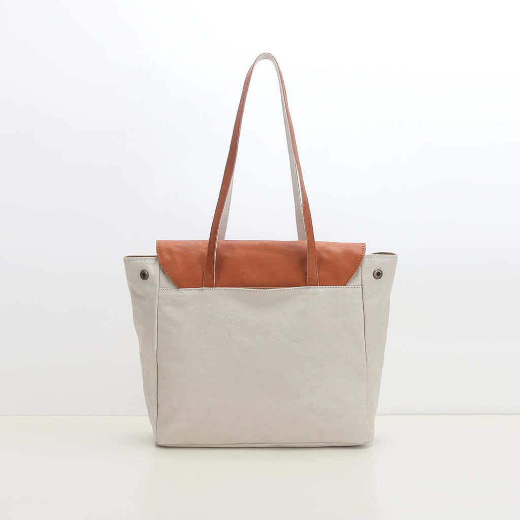 Back view of white canvas tote bag with leather detail.