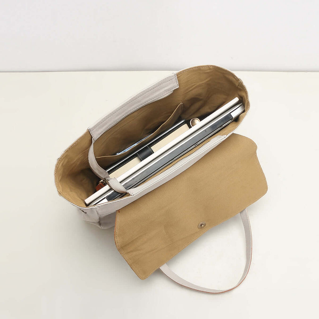 Canvas tote bag showing laptop and books inside.