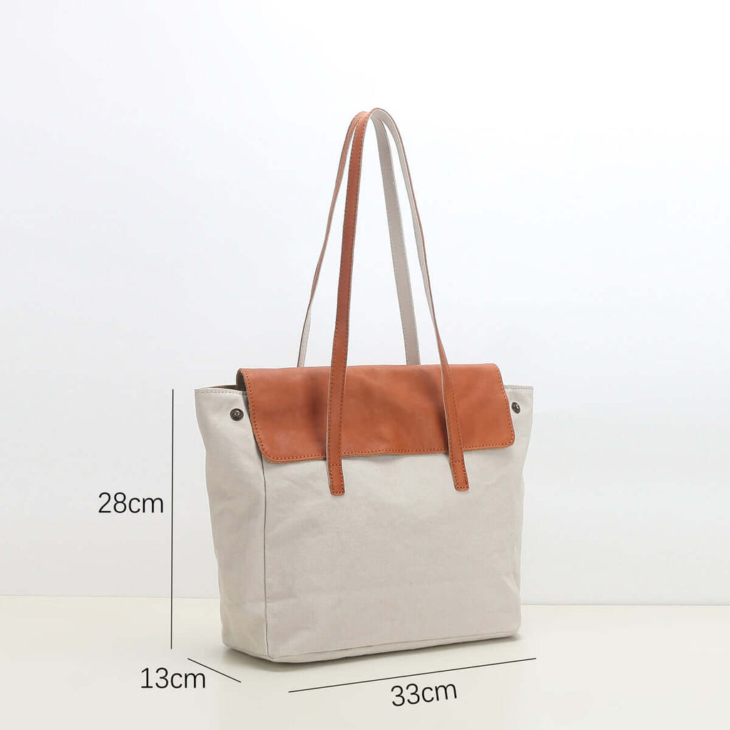 White canvas tote bag with brown leather patch and measurements.