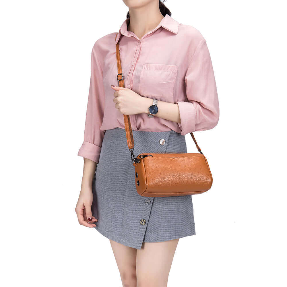 Brown leather crossbody bag featuring a modern minimalist design and spacious interior.